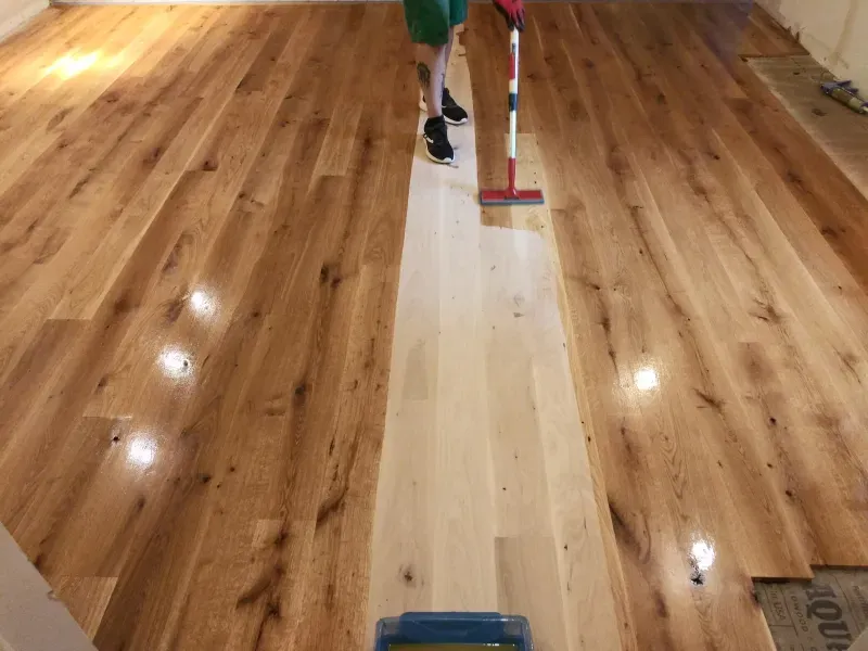 A person is cleaning a wooden floor with a mop
