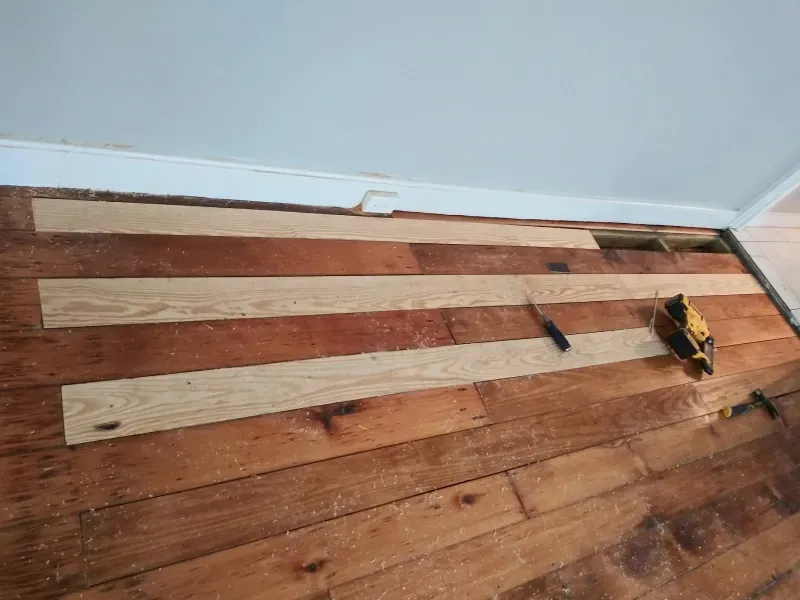 A wooden floor with a drill and a ruler on it.
