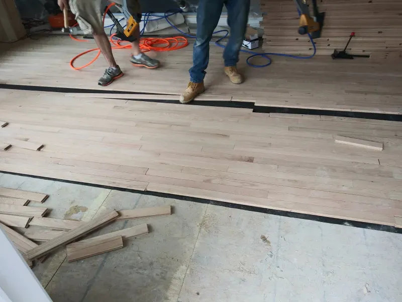 A group of men are working on a wooden floor