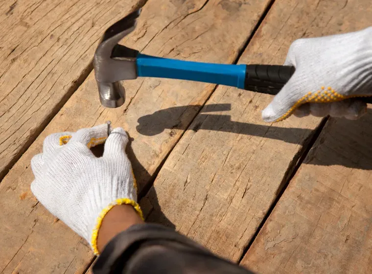 A person is using a hammer to hammer a nail into a piece of wood.